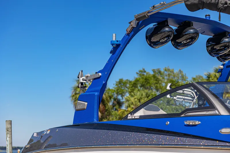 Slide: The Image of Blue 2017 Malibu M235 boat with speakers, against a clear sky backdrop. - 33