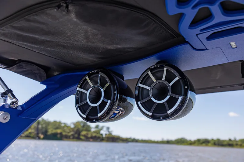 Slide: The Image of 2017 Malibu M235 boat speakers under blue canopy, overlooking a scenic water view. - 38