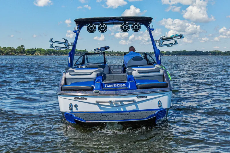 Slide: The Image of 2017 Malibu M235 boat cruising on a lake under a clear blue sky. - 4