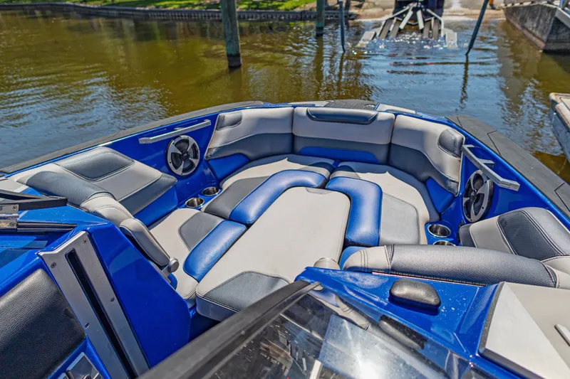 Slide: The Image of 2017 Malibu M235 boat interior with blue and gray seating, docked by the water. - 46