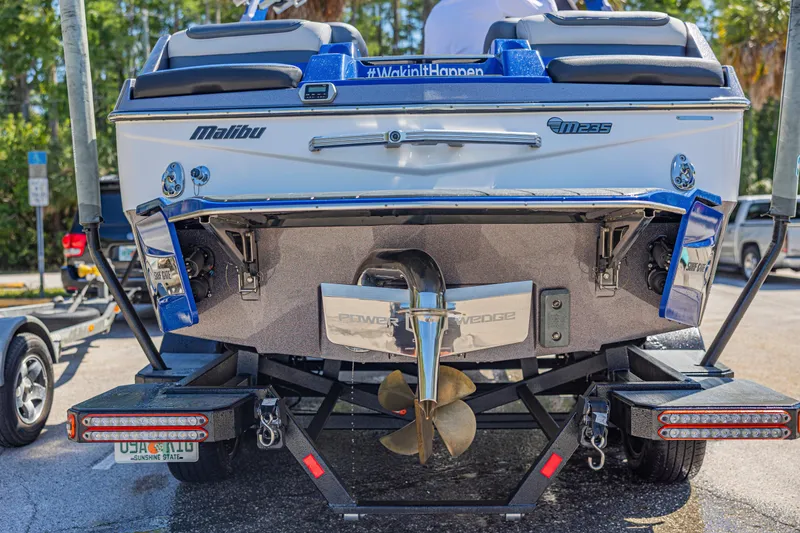 Slide: The Image of Rear view of a 2017 Malibu M235 boat on a trailer, showcasing propeller and branding. - 47