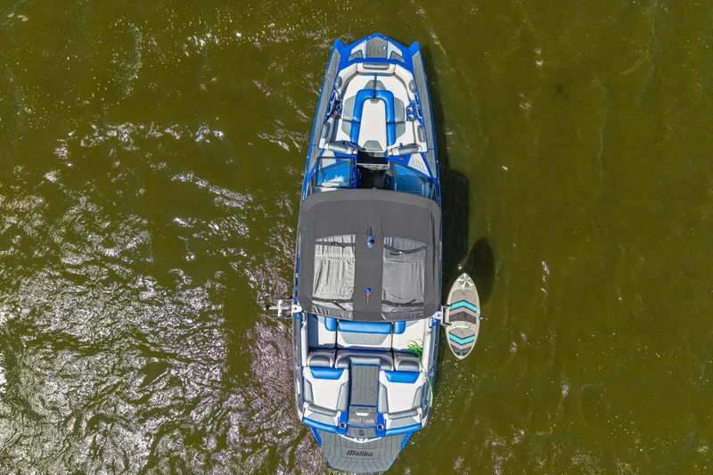 Slide: The Image of Overhead view of a 2017 Malibu M235 boat on water with a surfboard. - 5