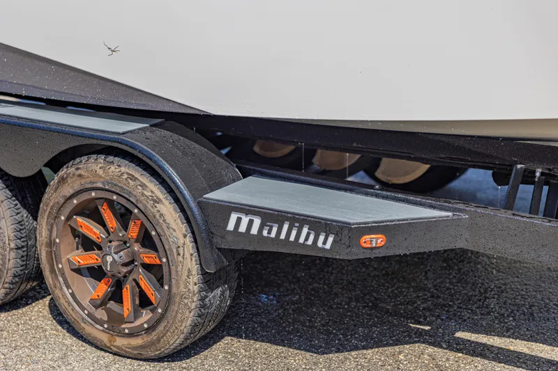 Slide: The Image of 2017 Malibu M235 trailer with custom orange-accented wheels on wet pavement. - 52