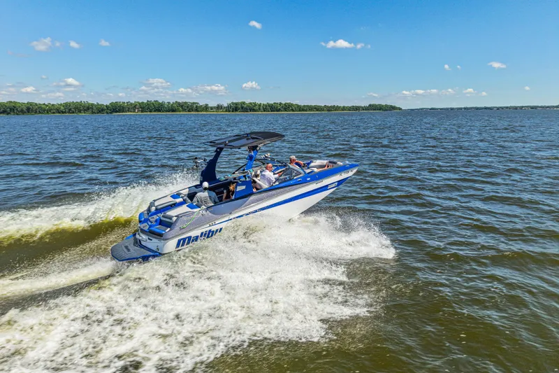 Slide: The Image of 2017 Malibu M235 boat cruising on a sunny lake with passengers enjoying the ride. - 7