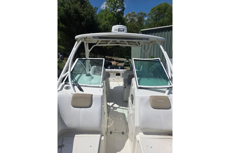 The Image of 2016 Sailfish 275 DC boat interior with dual consoles and seating, surrounded by greenery. - 0