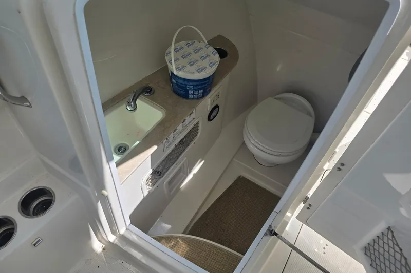 Slide: The Image of 2016 Sailfish 275 DC boat bathroom with sink, toilet, and cleaning supplies. - 4