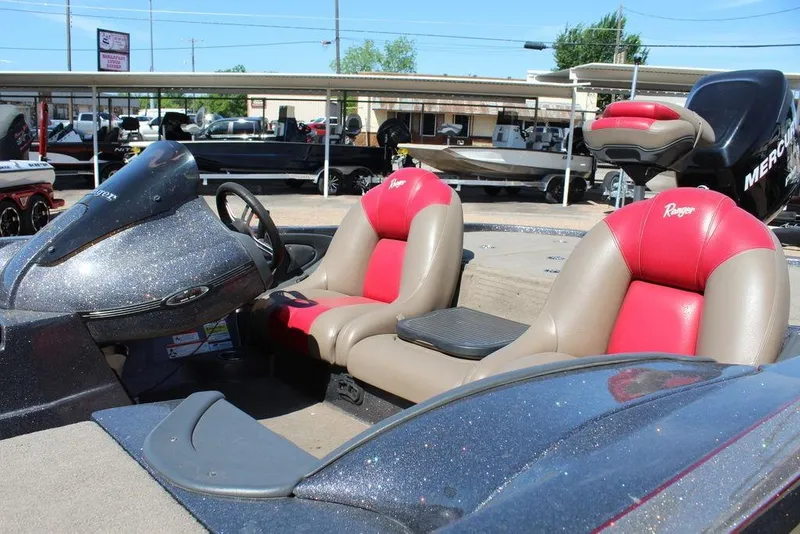 Slide: The Image of 2011 Ranger Z120 Comanche boat interior with red and beige seats, parked outdoors. - 12