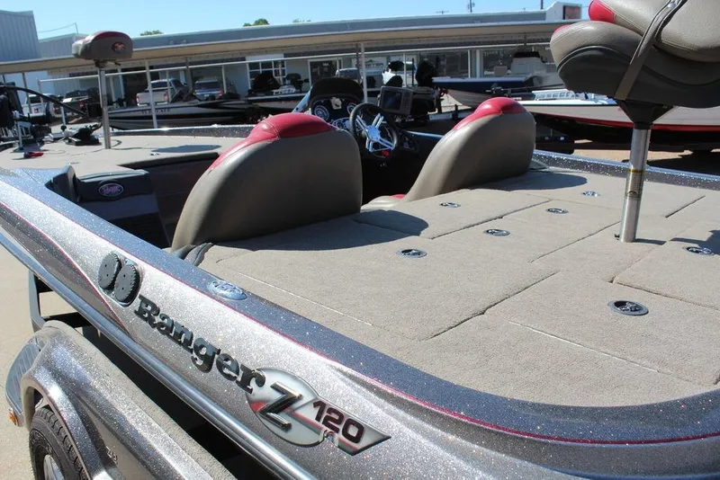 Slide: The Image of 2011 Ranger Z120 Comanche boat with spacious deck and seating, parked outdoors. - 5