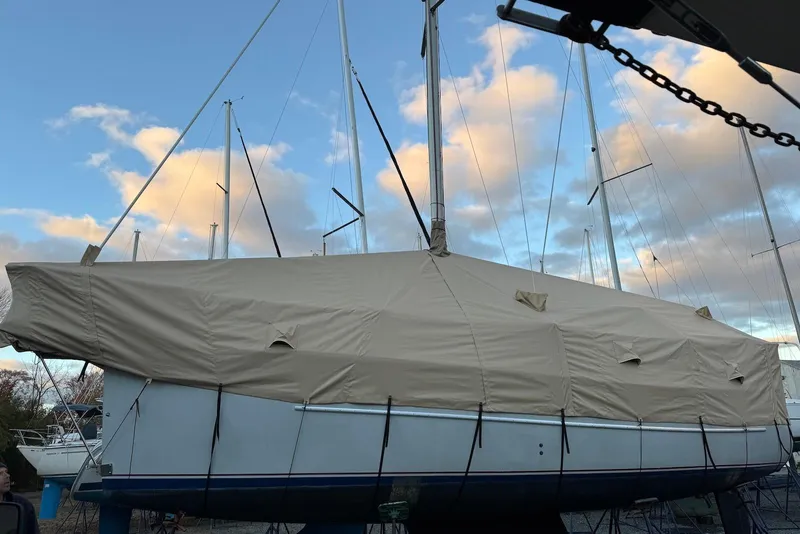 Slide: The Image of 1999 Hake Yachts Seaward Eagle 32 sailboat covered, docked under a cloudy sky. - 2