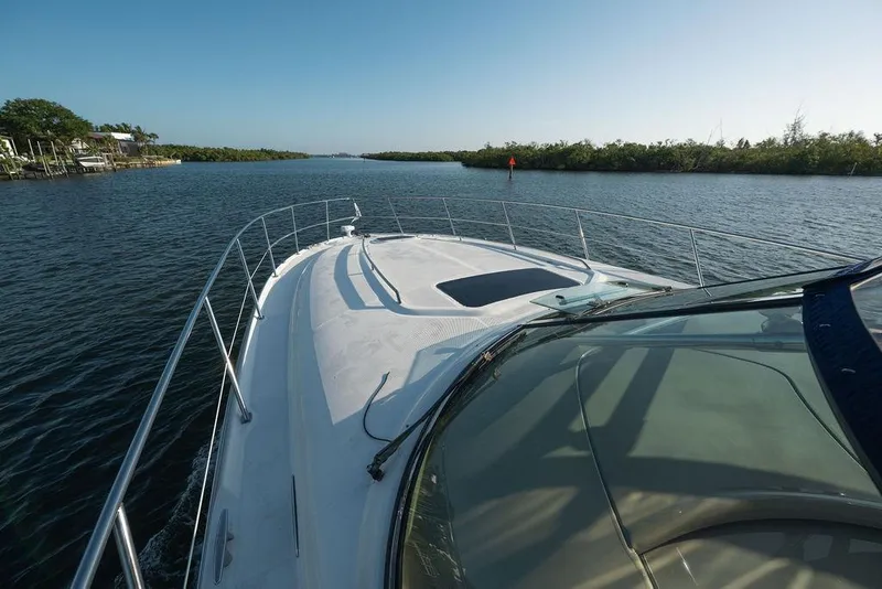 Slide: The Image of 2005 Sea Ray 420 Sundancer cruising on a serene waterway under clear blue skies. - 24