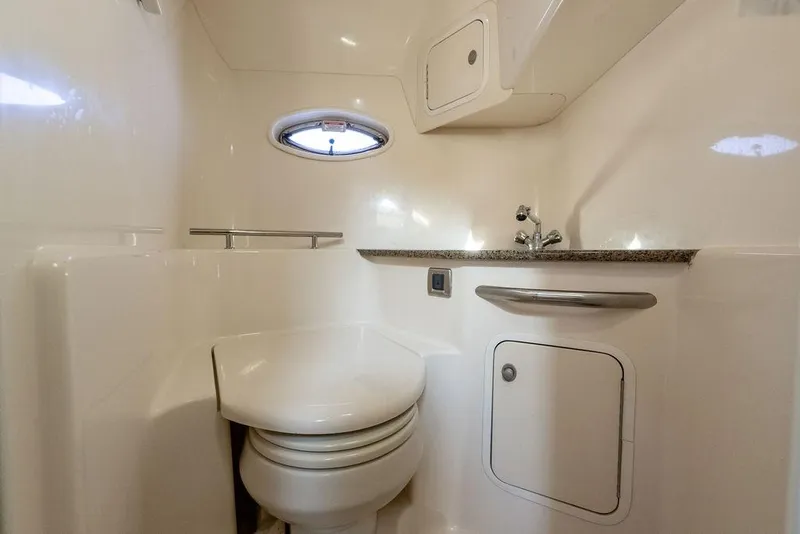 Slide: The Image of 2005 Sea Ray 420 Sundancer bathroom with compact design, featuring a toilet, sink, and porthole window. - 38