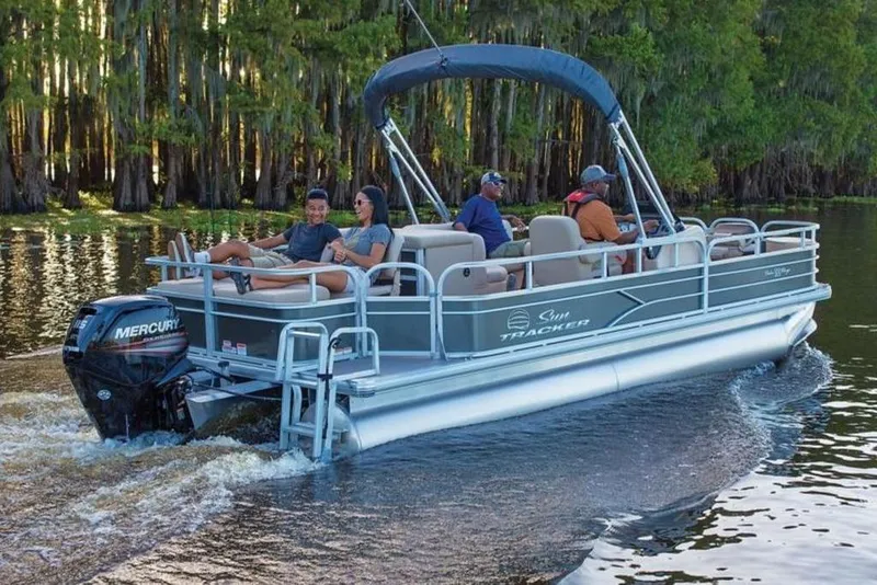The Image of 2017 Sun Tracker Fishin' Barge 22 DLX pontoon boat cruising on a scenic lake. - 1