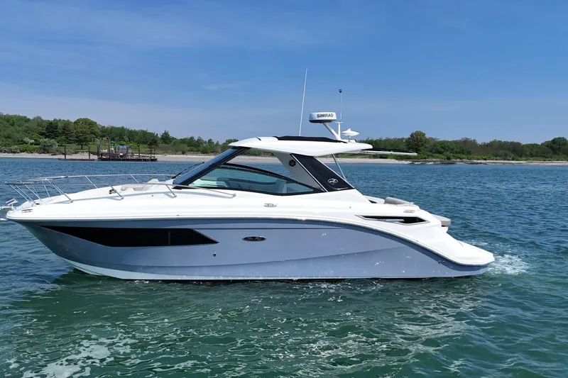 Slide: The Image of 2023 Sea Ray Sundancer 320 cruising on a sunny day near a lush shoreline. - 1