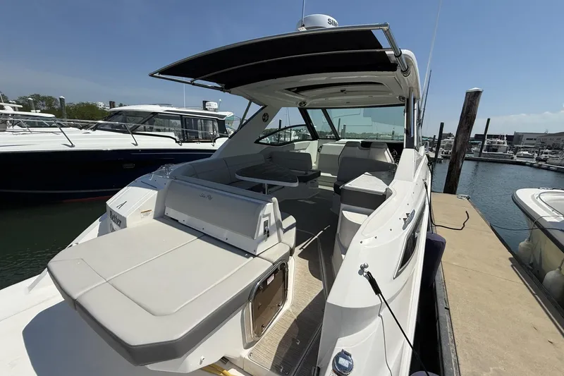 Slide: The Image of 2023 Sea Ray Sundancer 320 yacht docked at marina, showcasing spacious seating and sleek design. - 10