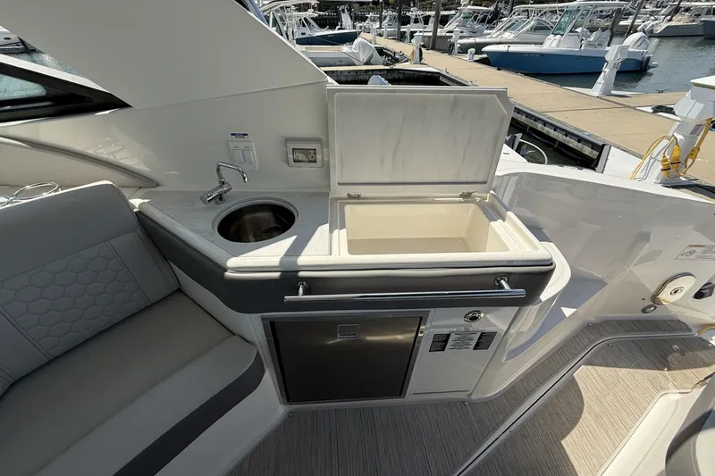 Slide: The Image of 2023 Sea Ray Sundancer 320 yacht interior with sink, cooler, and seating at marina. - 15