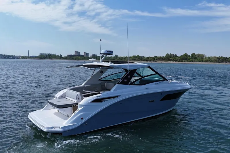 Slide: The Image of 2023 Sea Ray Sundancer 320 yacht cruising on a calm, scenic waterway. - 6