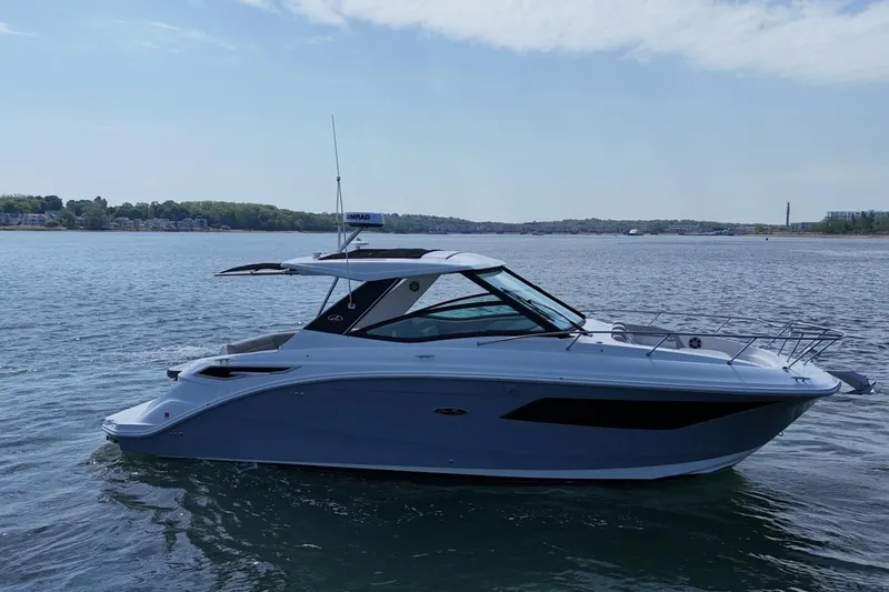 Slide: The Image of 2023 Sea Ray Sundancer 320 yacht cruising on a calm lake under a clear sky. - 7