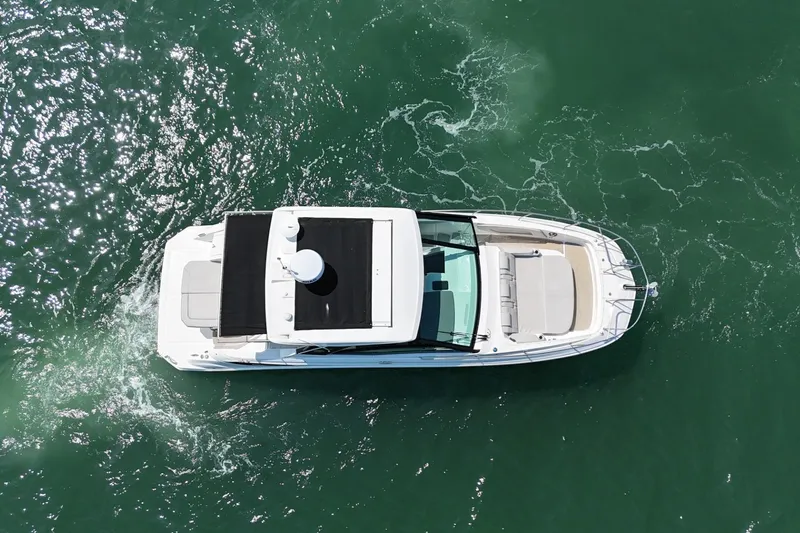 Slide: The Image of Overhead view of 2023 Sea Ray Sundancer 320 cruising on clear green water. - 8
