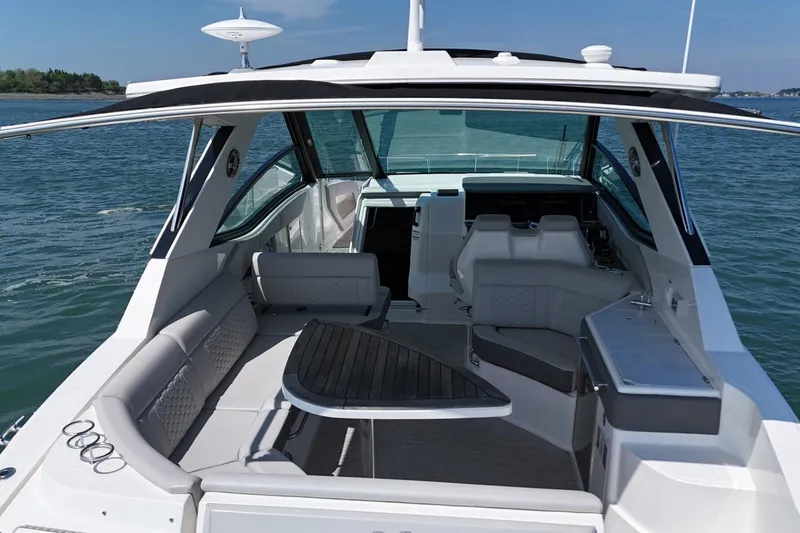 Slide: The Image of 2023 Sea Ray Sundancer 320 boat interior with seating and helm, on calm water. - 9
