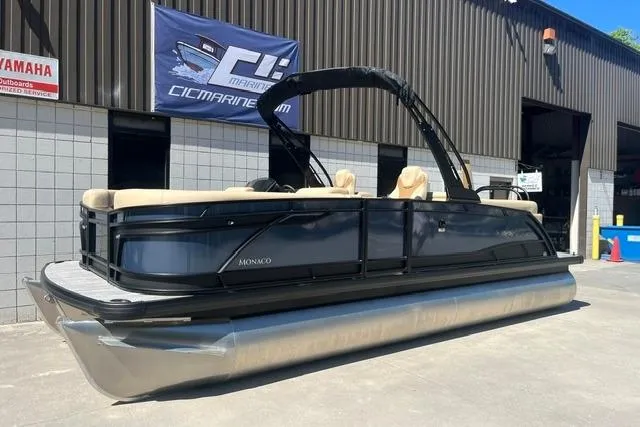 The Image of 2026 Godfrey Monaco 235 SB pontoon boat displayed outside a marine dealership. - 1