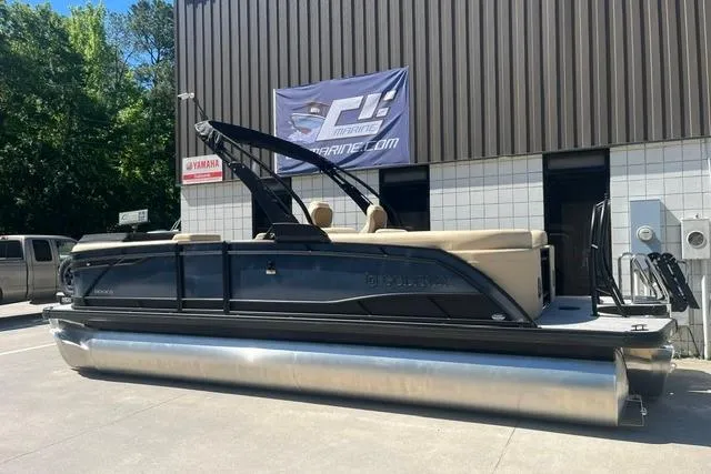Slide: The Image of 2026 Godfrey Monaco 235 SB pontoon boat parked outside a marine dealership. - 3