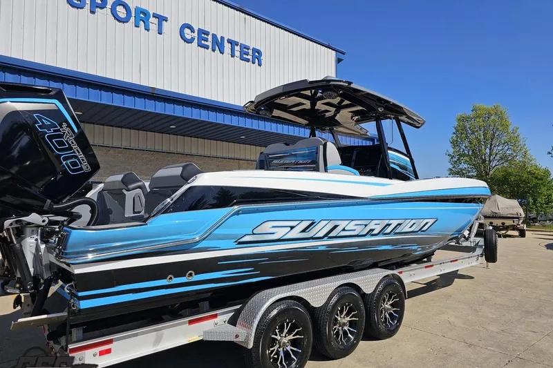 Slide: The Image of 2025 Sunsation 32 CCX boat with blue and black design at a sport center. - 10