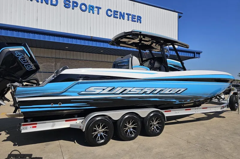 Slide: The Image of 2025 Sunsation 32 CCX boat on trailer at dealership, featuring sleek blue and black design. - 11