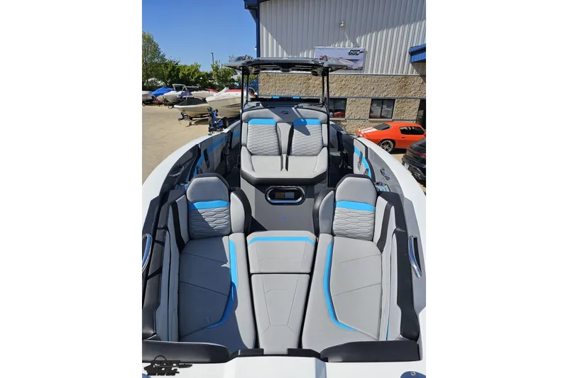 Slide: The Image of 2025 Sunsation 32 CCX boat interior with gray and blue seating, parked outdoors. - 20