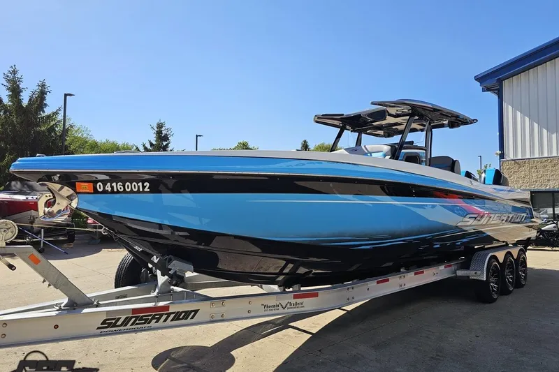 Slide: The Image of 2025 Sunsation 32 CCX powerboat on trailer, sleek blue design, parked outdoors. - 21