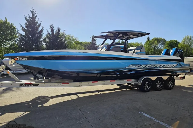 Slide: The Image of 2025 Sunsation 32 CCX boat on trailer, sleek blue design, parked outdoors. - 23