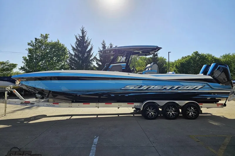 Slide: The Image of 2025 Sunsation 32 CCX boat on trailer, sleek blue design, parked outdoors. - 24