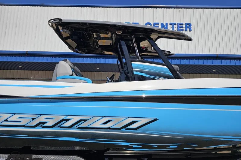 Slide: The Image of 2025 Sunsation 32 CCX boat with sleek blue and white design, docked near a marine center. - 4