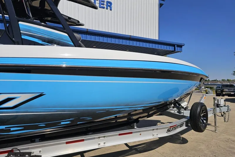 Slide: The Image of 2025 Sunsation 32 CCX boat in blue and white on a trailer outside a building. - 5