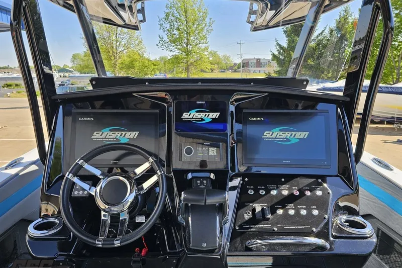 Slide: The Image of 2025 Sunsation 32 CCX boat dashboard with dual Garmin displays and sleek steering wheel. - 79