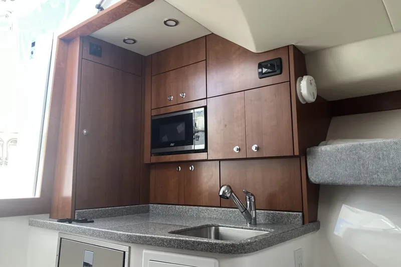 Slide: The Image of 2024 Albemarle 30 Express boat interior with modern kitchenette and wooden cabinetry. - 10