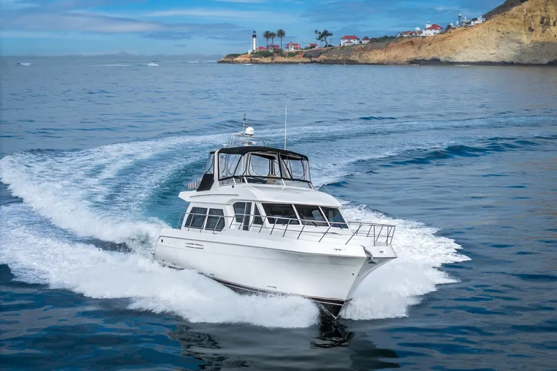 Slide: The Image of 2006 Navigator 5100 yacht cruising near a scenic coastal lighthouse. - 2