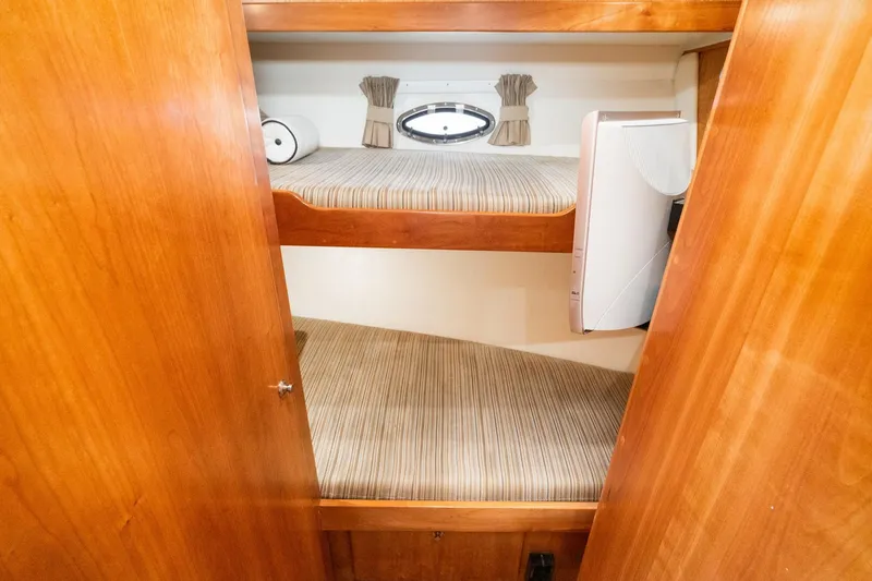 Slide: The Image of Bunk beds in 2006 Navigator 5100 yacht cabin with wood paneling and small window. - 41
