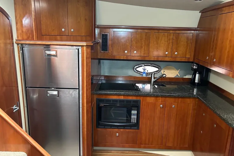Slide: The Image of Luxurious 2006 Cruisers Yachts 460 Express kitchen with wood cabinetry and stainless steel appliances. - 5