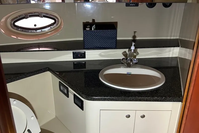 Slide: The Image of 2006 Cruisers Yachts 460 Express bathroom with sink, countertop, and porthole window. - 9