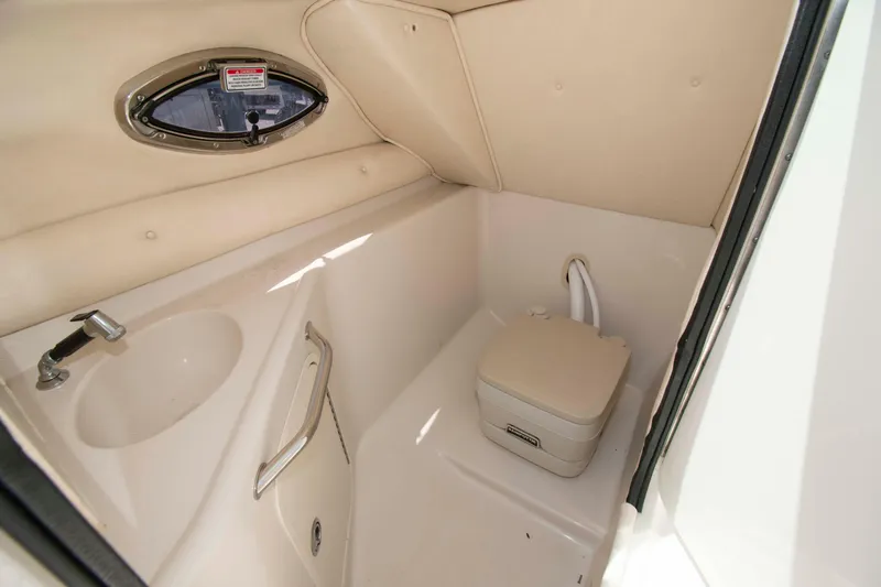Slide: The Image of 2005 Sea Ray 240 Sundeck interior with compact marine toilet and sink. - 10