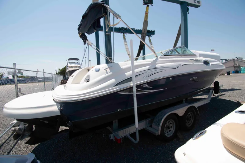 Slide: The Image of 2005 Sea Ray 240 Sundeck boat on trailer, parked outdoors under clear sky. - 2