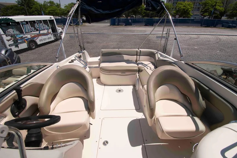 Slide: The Image of 2005 Sea Ray 240 Sundeck boat interior with beige seating and steering wheel. - 7