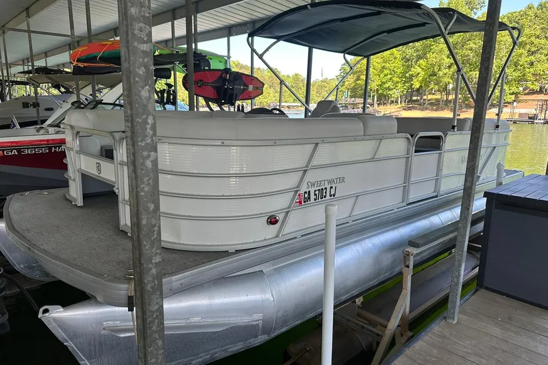 The Image of 2022 Godfrey Sweetwater 2286 SB pontoon boat docked under a covered marina. - 0