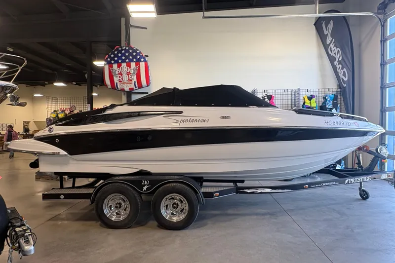 The Image of 2008 Crownline 210 LS boat on trailer in showroom, black and white design. - 3