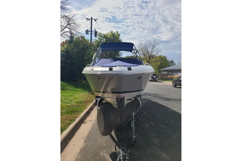 Slide: The Image of 2009 Bryant 268 boat on trailer, parked on a suburban street under a cloudy sky. - 11