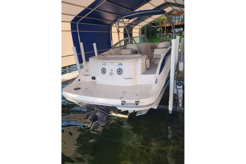 Slide: The Image of 2009 Bryant 268 boat docked under a canopy, rear view showing seating and motor. - 2