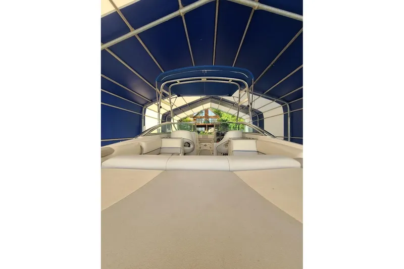 Slide: The Image of 2009 Bryant 268 boat interior under blue canopy, showcasing seating and helm area. - 3
