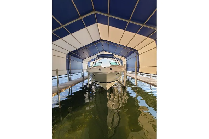 Slide: The Image of 2009 Bryant 268 boat docked under a blue and white canopy on calm water. - 9