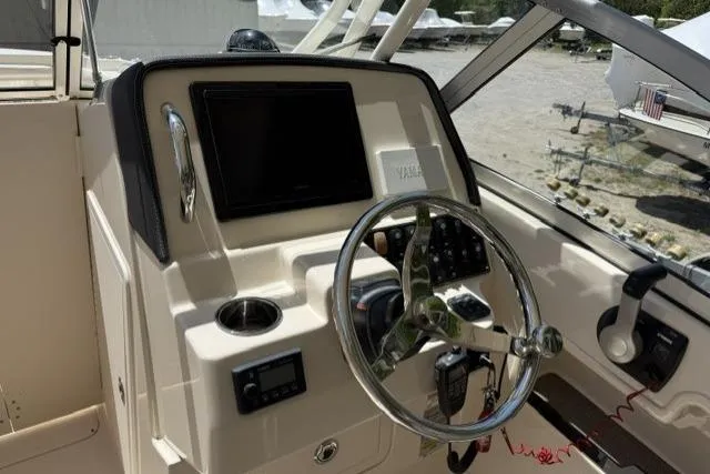 Slide: The Image of 2017 Grady-White Freedom 235 boat helm with steering wheel and navigation controls. - 12