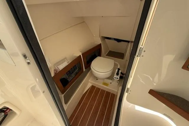 Slide: The Image of 2017 Grady-White Freedom 235 boat interior with compact marine toilet and wooden flooring. - 18